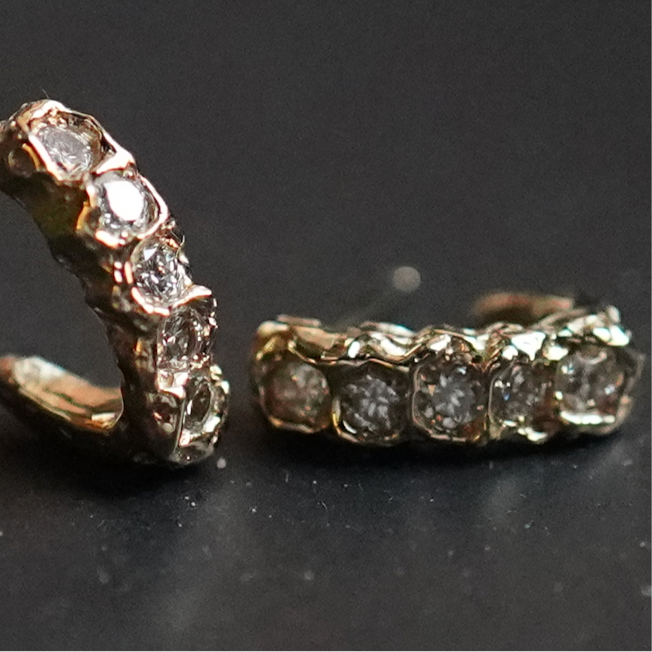 Pair of gold earrings with diamond accents on a dark background