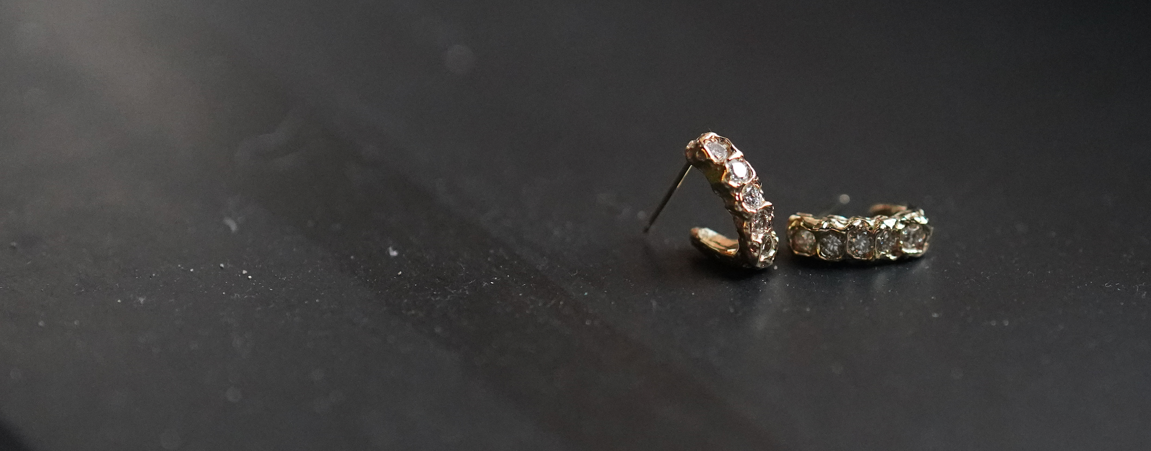 Pair of yellow gold diamond-studded earrings on a black background