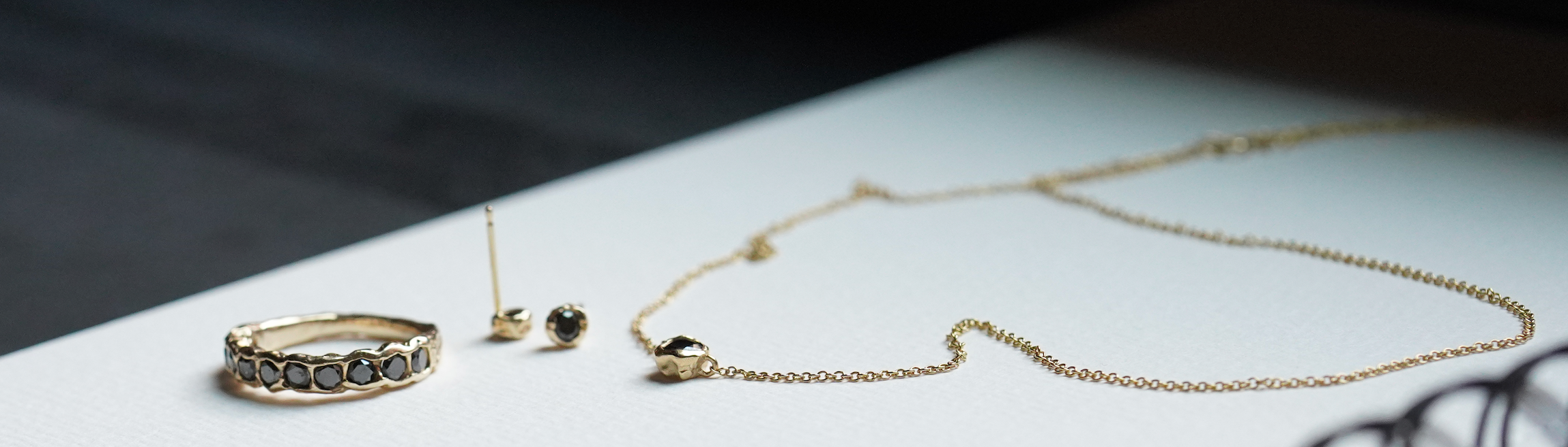 Gold jewelry including a ring, earrings, and necklace on a white surface.